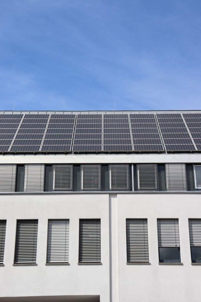A modern building equipped with solar panels on the roof against a clear blue sky.